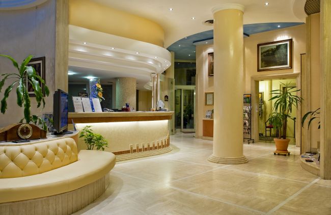 Lobby dell'hotel con reception moderna e piante.
