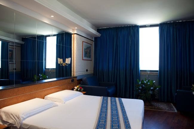 Camera d'albergo con letto matrimoniale e tende blu.