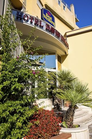 Ingresso di un hotel con piante e insegna.