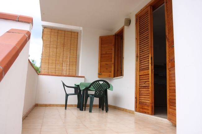 Balcone con tavolo e sedie verdi.