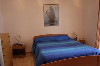 Camera da letto con letto matrimoniale e quadro nautico sul muro.