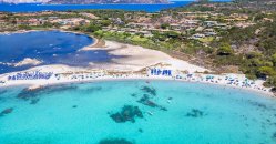 Spiaggia con mare turchese e ombrelloni allineati lungo la riva.