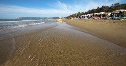 Spiaggia ampia con mare, ombrelloni e cielo sereno.