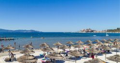 Spiaggia con ombrelloni di paglia e mare blu.