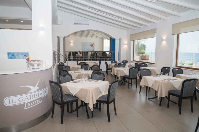 Ristorante elegante con tavoli apparecchiati e sedie nere.