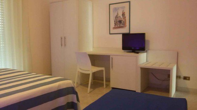 Camera con armadio, scrivania, sedia e TV.