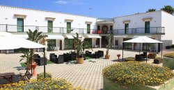 Cortile di un hotel con ombrelloni, piante e sedute all'aperto.