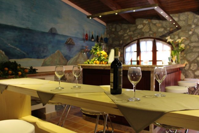 Bar con bottiglie, tavoli e decorazioni marine.
