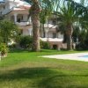 Edificio con balconi e palme in giardino vicino a una piscina.