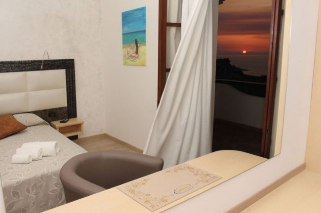 Camera da letto con vista su un tramonto sul mare.