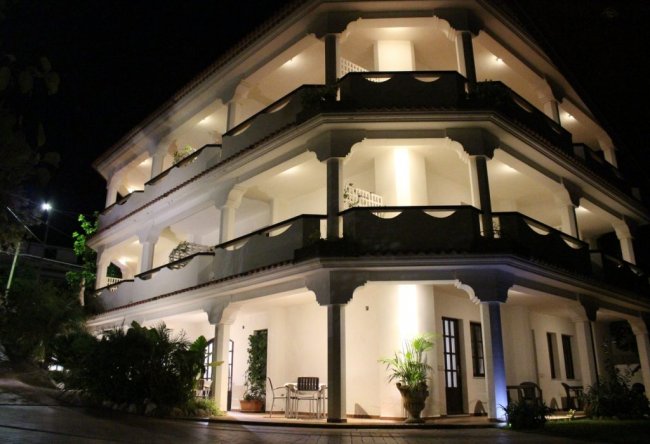 Edificio a tre piani con balconi illuminati di notte.
