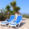 Due sdraio blu su terrazza con vista giardino e mare.
