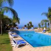 Piscina con lettini e palme, sotto un cielo blu.