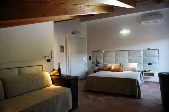 Camera con letto matrimoniale, divano e travi in legno.