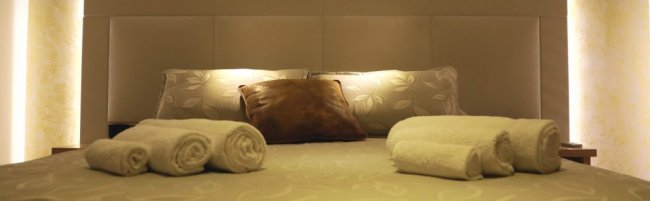 Un letto con asciugamani arrotolati e cuscini decorativi.