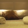 Un letto con asciugamani arrotolati e cuscini decorativi.