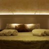 Un letto con testiera illuminata e asciugamani arrotolati.