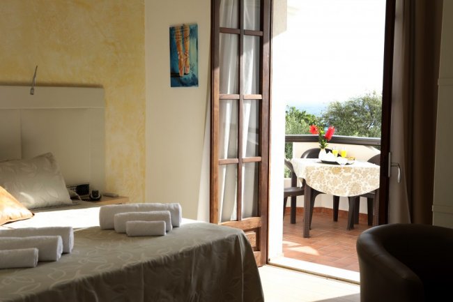 Una camera con letto e balcone con tavolo apparecchiato.