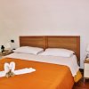 Letto matrimoniale con copriletto arancione e asciugamani a cigno.