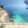 Scogliera e spiaggia con mare blu cristallino.