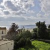 Vista sul mare con alberi e edifici al tramonto.