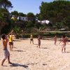 Persone giocano a pallavolo su un campo di sabbia.