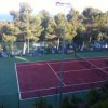 Campo da tennis rosso tra alberi.