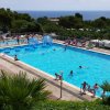 Piscina all'aperto con vista mare, molte persone in relax.