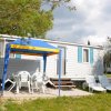 Casa mobile bianca con tavolo esterno e sedie sotto un tendalino.
