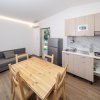 Soggiorno moderno con tavolo in legno e cucina attrezzata.