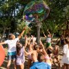 Bambini giocano con una bolla gigante in un parco.