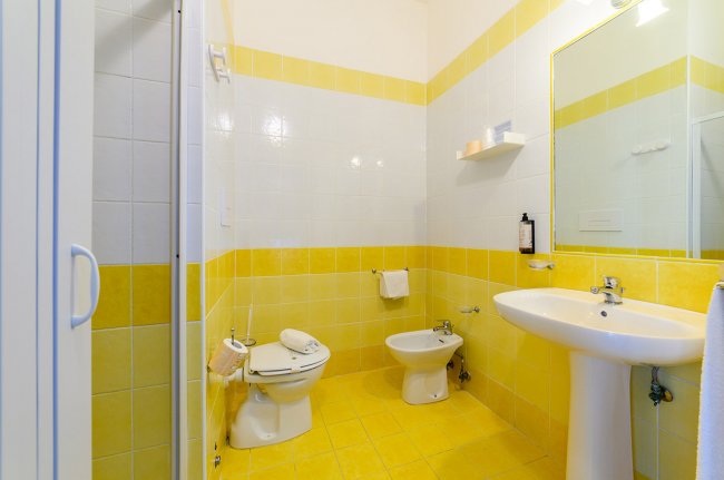 Bagno con piastrelle gialle, lavabo e bidet.