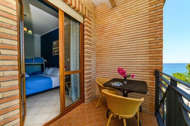 Terrazza con tavolo, sedie e vista sul mare.