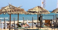 Spiaggia con ombrelloni di paglia e sedie a sdraio vicino al mare.