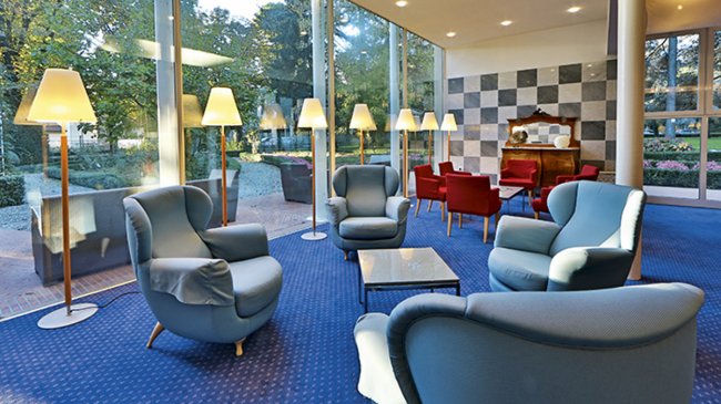 Salotto con poltrone blu e lampade alte.