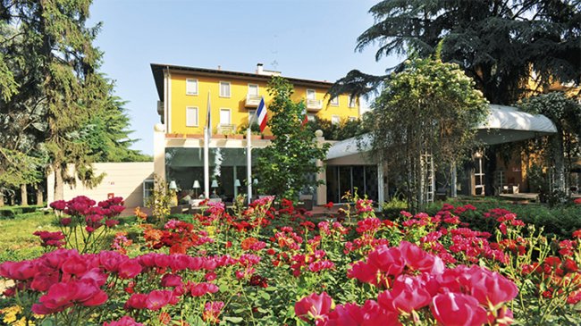 Giardino con fiori rosa e un edificio giallo.