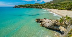 Spiaggia con mare turchese e scogli.