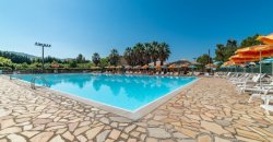 Ampia piscina all'aperto con sedie a sdraio e ombrelloni arancioni.