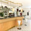 Angolo bar con bancone curvo, sgabelli bianchi e decorazioni vegetali. Bottiglie sugli scaffali.