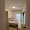 Stanza d'hotel con due letti singoli, finestra con tende bianche, TV a muro e scrivania.