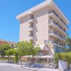 Edificio a più piani con balconi, circondato da alberi in una giornata di sole.