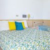 Camera con letto matrimoniale e letti singoli, copriletto floreale e cuscini colorati.