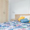 Camera da letto con armadio, copriletto floreale e cuscini colorati.