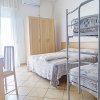 Camera con letto matrimoniale e letti a castello, tende bianche e mobilio chiaro.