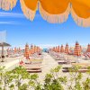 Spiaggia con ombrelloni e lettini allineati.
