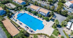 Vista dall'alto di una piscina circondata da sedie a sdraio e verde.
