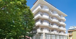 Struttura residenziale bianca accanto a un grande albero.