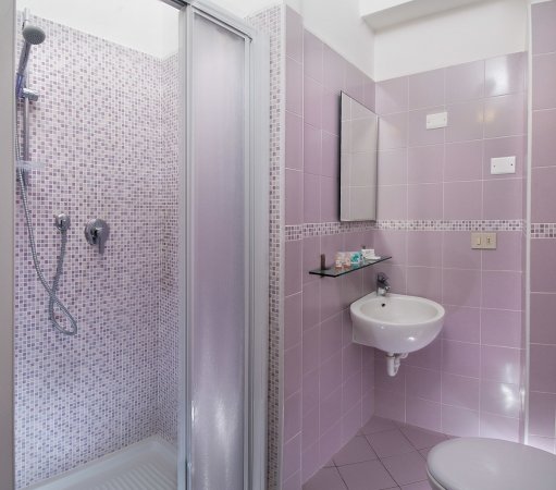 Bagno con piastrelle rosa e doccia.