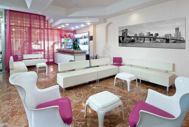 Sala con arredi moderni bianchi e rosa.