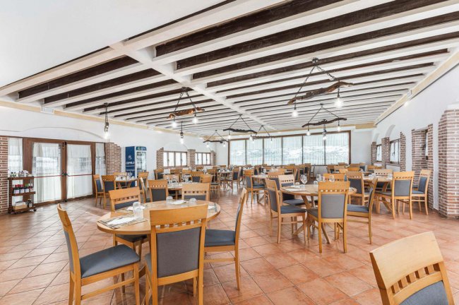 Sala da pranzo con sedie e tavoli in legno.